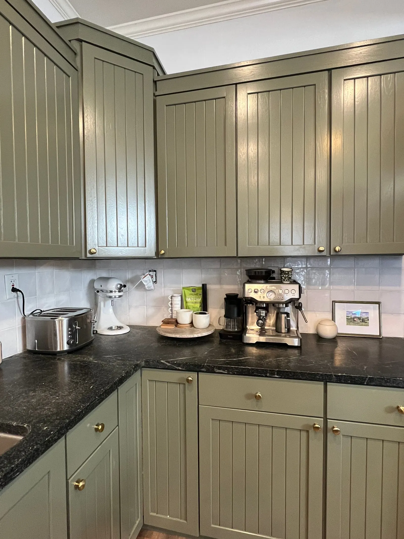 Close-up of repainted olive green cabinets with brass hardware