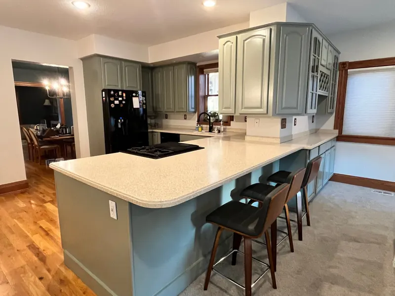 Repainted sage green cabinets with black kitchen island