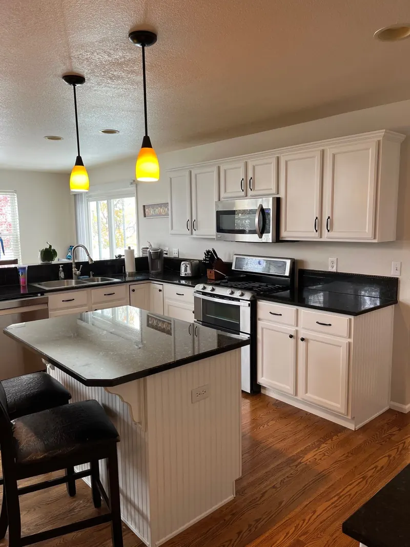 Repainted white kitchen cabinets with black granite counters